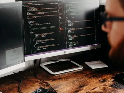 Code editor open on a large monitor on a wooden desk
